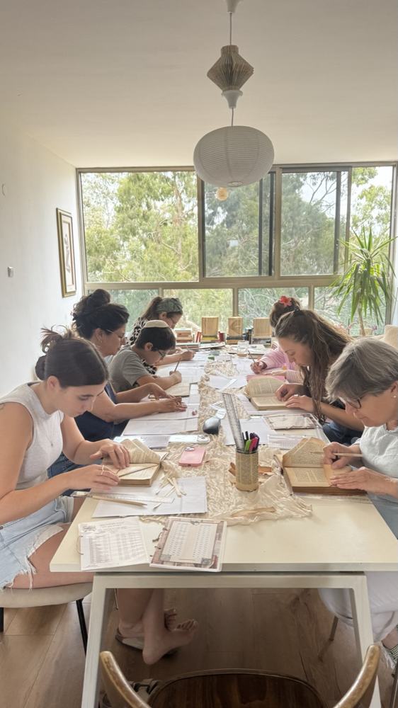 משתתפות בסדנת פיסול ספרים עובדות סביב שולחן ארוך