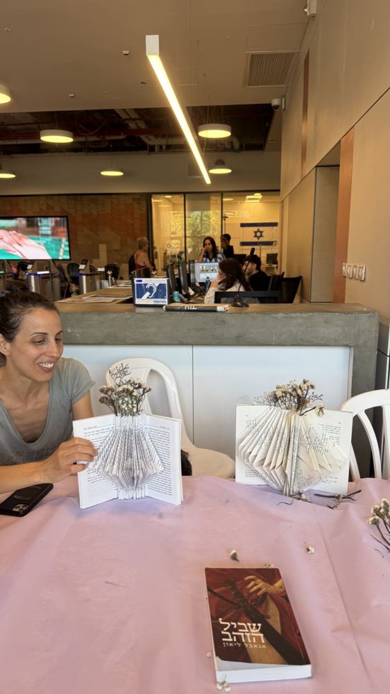 משתתפת ליד אגרטלי ספרים עם פרחים